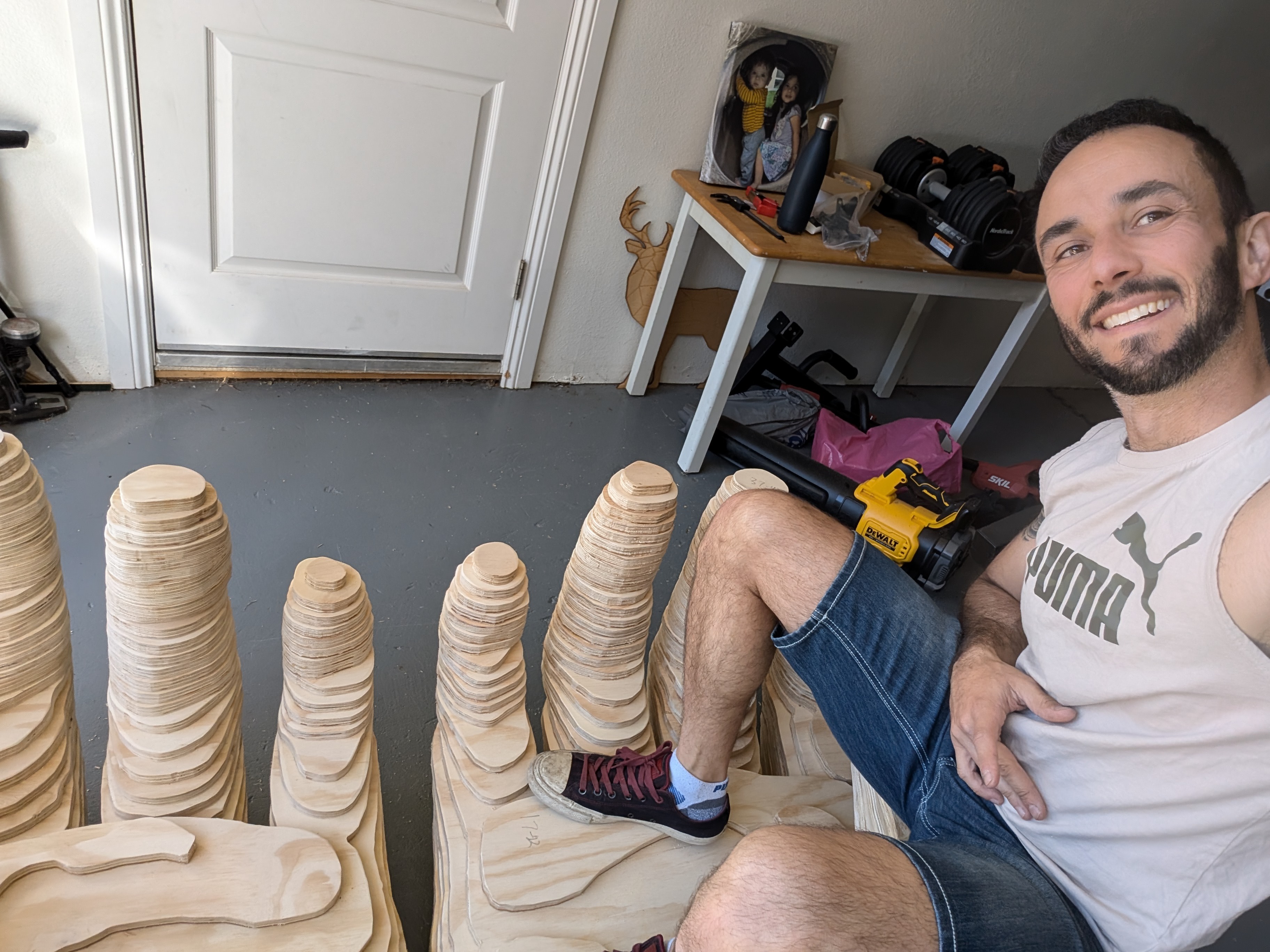 Vitaly sitting with layered wooden components for the Lover's Tree installation in his workshop